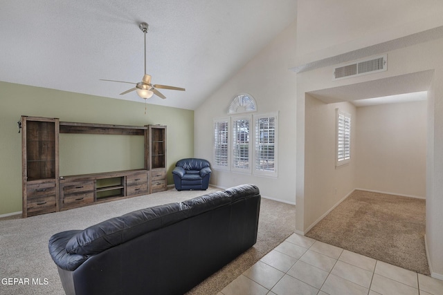 living room with a ceiling fan, visible vents, baseboards, high vaulted ceiling, and light carpet