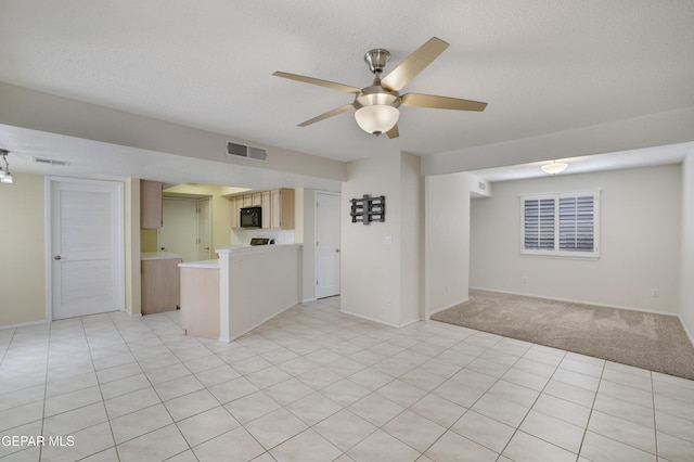 interior space with baseboards, ceiling fan, a textured ceiling, and visible vents