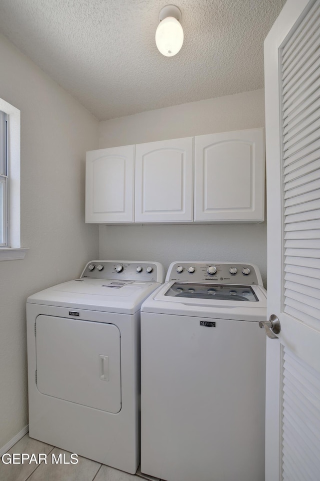 laundry room with a textured ceiling, cabinet space, and washer and clothes dryer