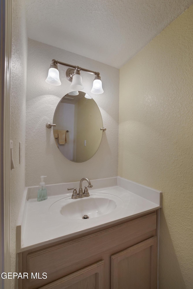 bathroom featuring vanity and a textured wall