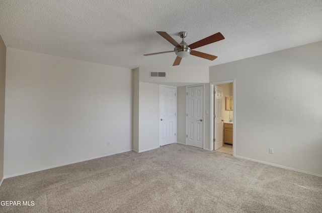 unfurnished bedroom featuring visible vents, ensuite bathroom, baseboards, light colored carpet, and a textured ceiling