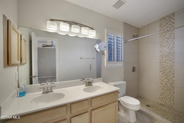 bathroom featuring visible vents, a sink, toilet, and tiled shower