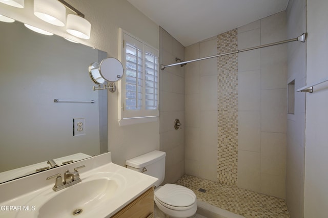 full bath featuring toilet, a tile shower, and vanity