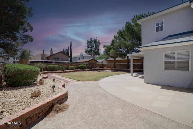yard at dusk featuring a fenced backyard and a patio area
