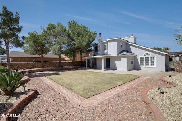 rear view of property with a patio area, stucco siding, a chimney, and fence