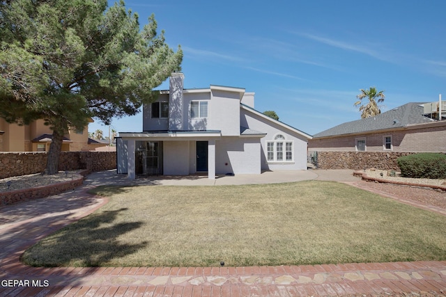 rear view of house with a patio, stucco siding, a yard, and fence