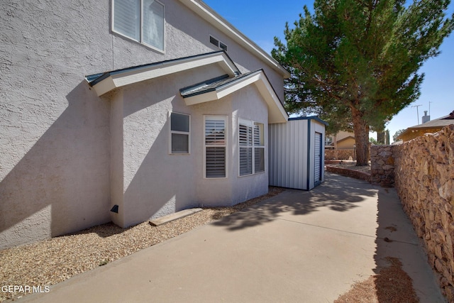 view of property exterior featuring a patio, fence, an outdoor structure, and stucco siding