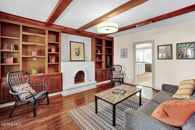 2723 Grant Ave, El Paso, TX 79930 - living area featuring dark wood-style floors, beamed ceiling, built in shelves, a textured ceiling, and a fireplace