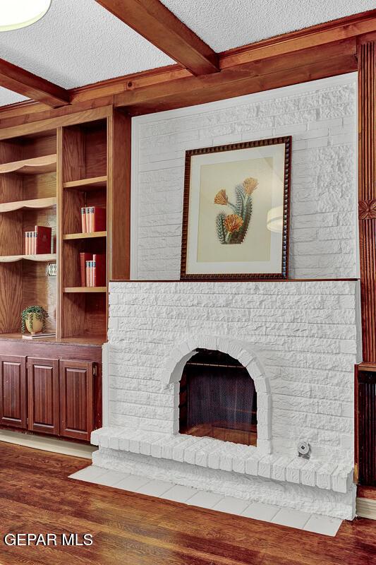 2723 Grant Ave, El Paso, TX 79930 - unfurnished living room with beamed ceiling, a textured ceiling, wood finished floors, and a fireplace