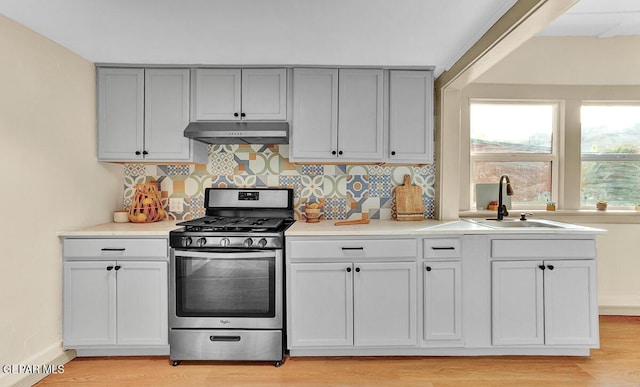 2723 Grant Ave, El Paso, TX 79930 - kitchen featuring stainless steel range with gas cooktop, under cabinet range hood, a sink, tasteful backsplash, and light wood-style flooring
