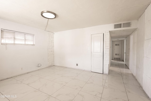 unfurnished room with marble finish floor and visible vents