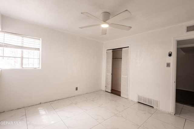 unfurnished bedroom featuring visible vents, a ceiling fan, marble finish floor, and a closet