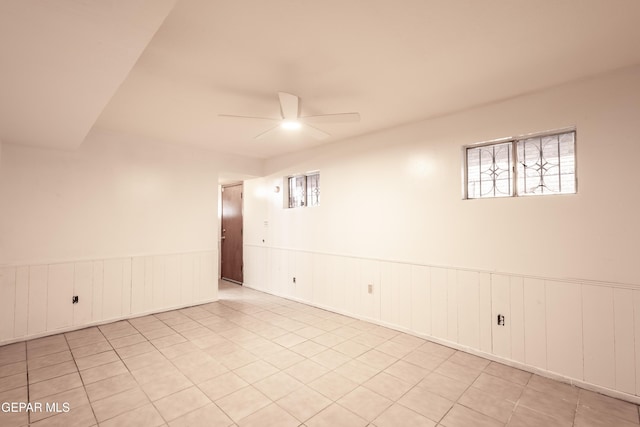 unfurnished room featuring tile patterned flooring, a ceiling fan, and wainscoting
