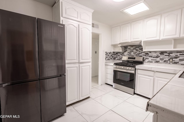 kitchen featuring marble finish floor, under cabinet range hood, white cabinets, tasteful backsplash, and stainless steel appliances