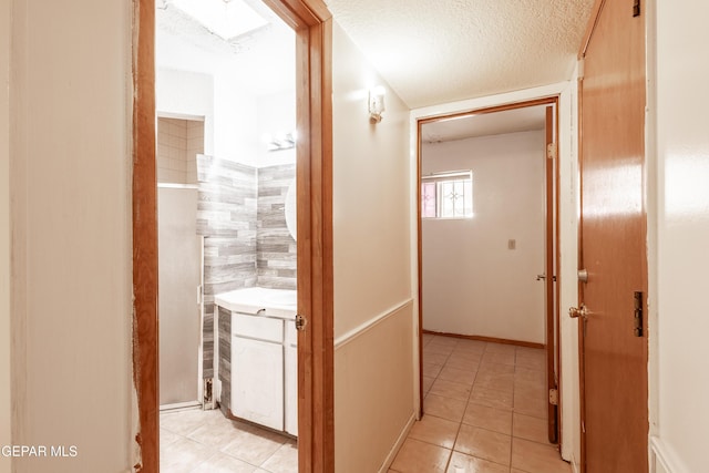 hall with a textured ceiling and light tile patterned floors