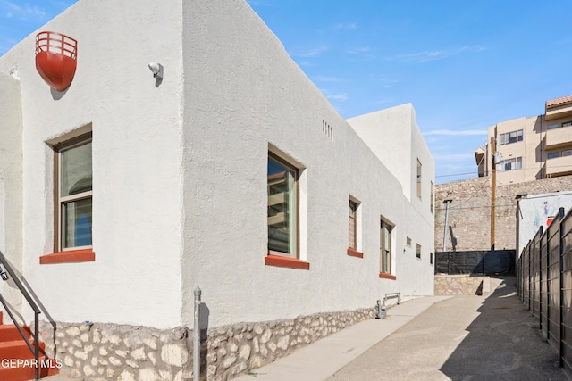 view of side of property featuring fence and stucco siding