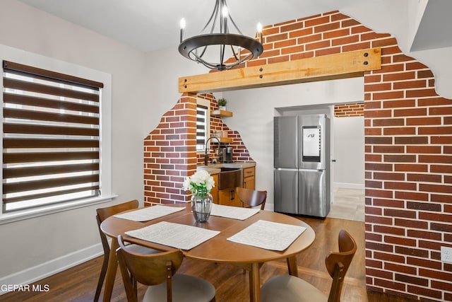 dining area featuring baseboards, an inviting chandelier, wood finished floors, and brick wall