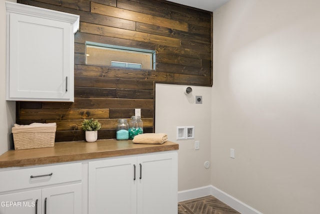 laundry area featuring wood walls, baseboards, hookup for a washing machine, electric dryer hookup, and cabinet space
