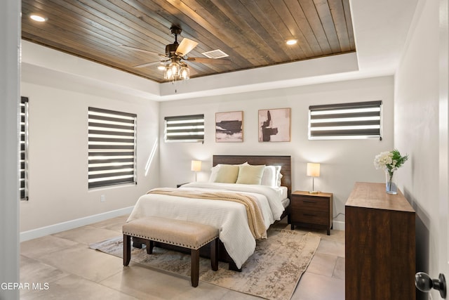 bedroom featuring wooden ceiling, baseboards, a tray ceiling, and light tile patterned flooring