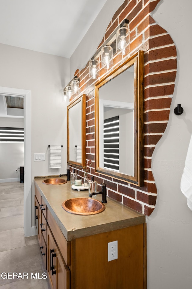 bathroom featuring double vanity, a sink, decorative backsplash, and baseboards