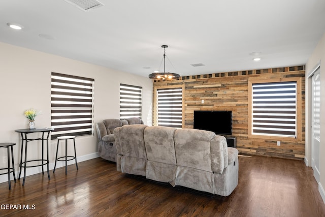 living area featuring baseboards, an accent wall, dark wood-style flooring, and visible vents