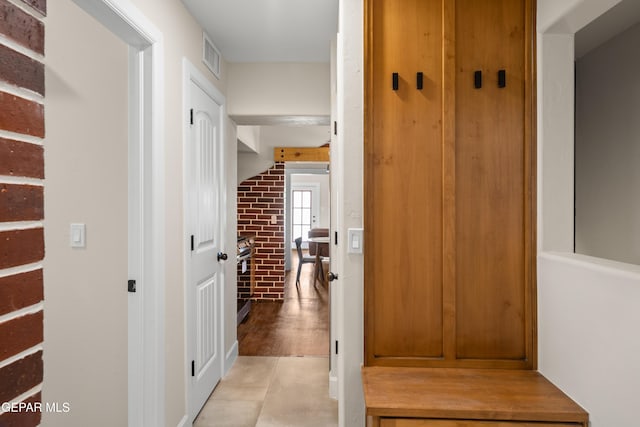 mudroom featuring brick wall and visible vents