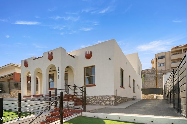 back of property with a porch, stucco siding, and fence