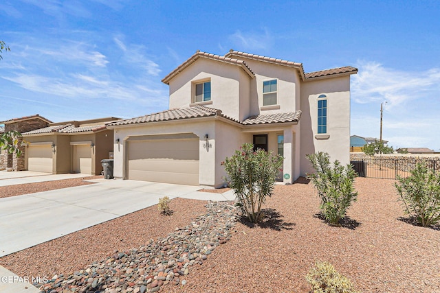 mediterranean / spanish house with fence, stucco siding, a tiled roof, concrete driveway, and an attached garage