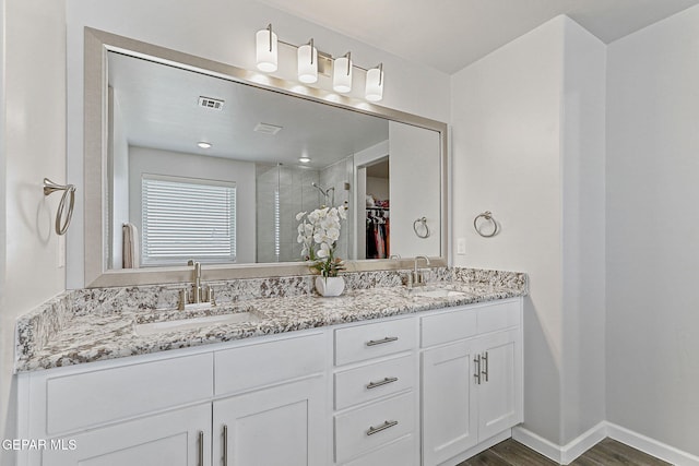 bathroom featuring a sink, a walk in closet, wood finished floors, and visible vents