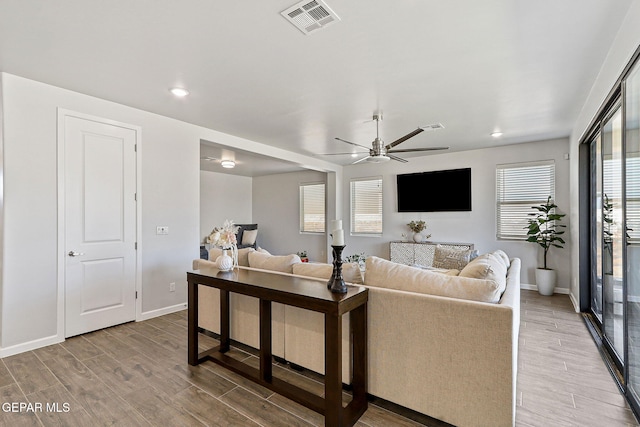living area featuring visible vents, light wood-style flooring, ceiling fan, and baseboards