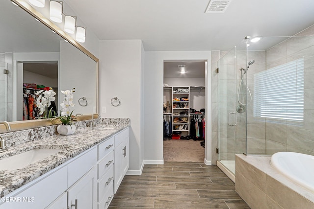 full bath featuring visible vents, a sink, a stall shower, and wood finished floors