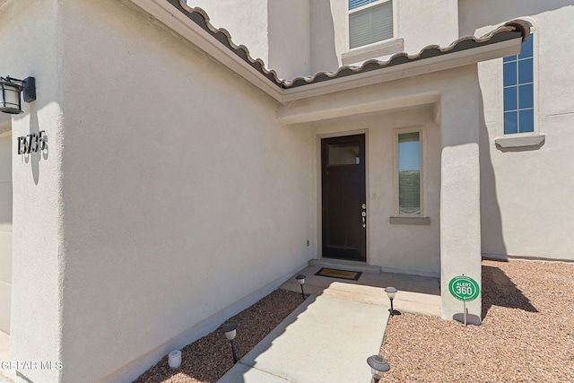 entrance to property featuring stucco siding and a tile roof