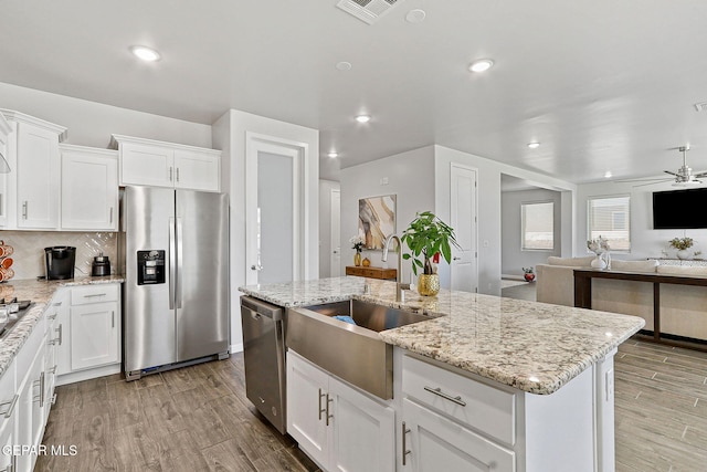 kitchen with open floor plan, appliances with stainless steel finishes, a sink, and wood finished floors