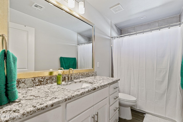 full bathroom featuring vanity, toilet, wood finished floors, and visible vents
