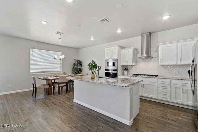 kitchen featuring dark wood-style flooring, visible vents, wall chimney exhaust hood, stainless steel appliances, and white cabinetry