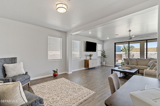 living area featuring a ceiling fan, baseboards, visible vents, and wood finished floors