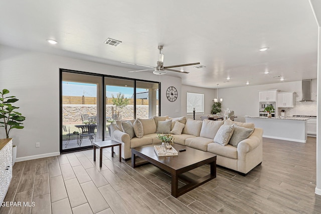 living area featuring ceiling fan, visible vents, baseboards, light wood finished floors, and recessed lighting