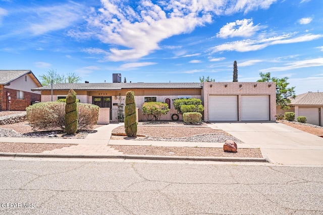 ranch-style home with an attached garage, concrete driveway, and brick siding