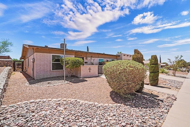 view of front of property featuring brick siding, a gate, and fence