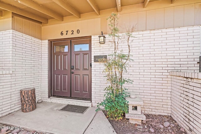 view of exterior entry featuring brick siding