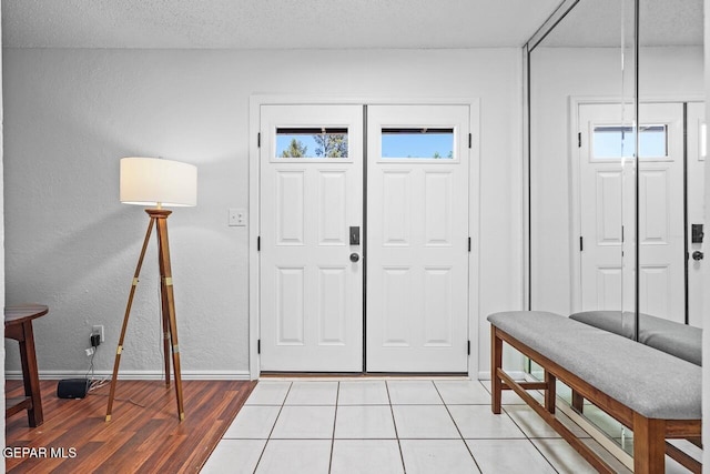 foyer entrance with plenty of natural light, baseboards, light wood finished floors, and a textured wall