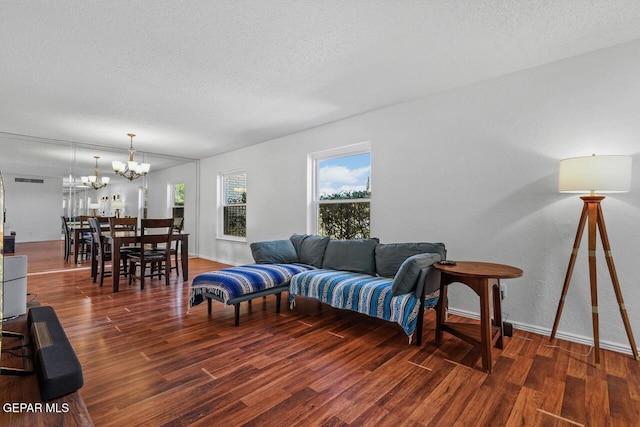 living area featuring wood finished floors, a chandelier, a textured ceiling, and baseboards