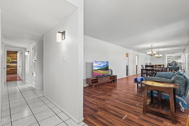 living area with a textured ceiling, a chandelier, wood finished floors, and baseboards