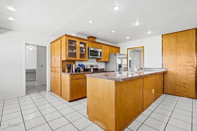 kitchen with stainless steel appliances, a peninsula, glass insert cabinets, a textured ceiling, and recessed lighting