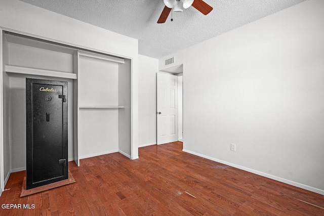 unfurnished bedroom featuring a closet, wood finished floors, a textured ceiling, and baseboards