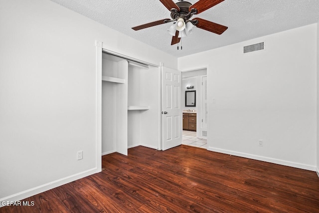 unfurnished bedroom with wood finished floors, a textured ceiling, baseboards, a ceiling fan, and a closet
