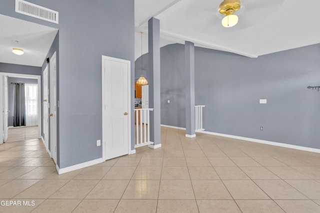 spare room with visible vents, baseboards, lofted ceiling, and tile patterned flooring
