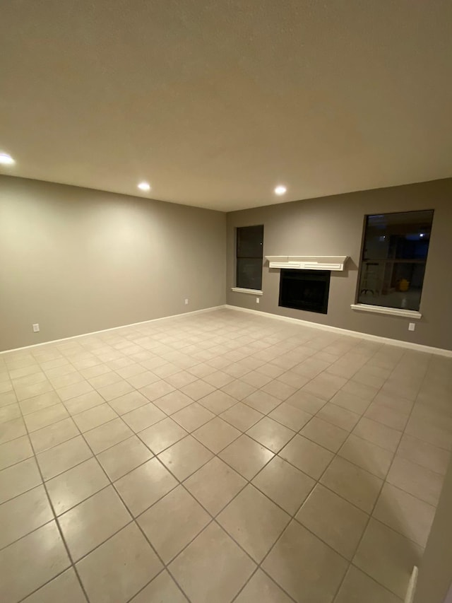 unfurnished living room featuring recessed lighting, baseboards, light tile patterned floors, and a fireplace