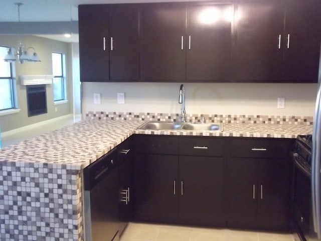 kitchen featuring an inviting chandelier, stainless steel dishwasher, a peninsula, stainless steel counters, and a sink
