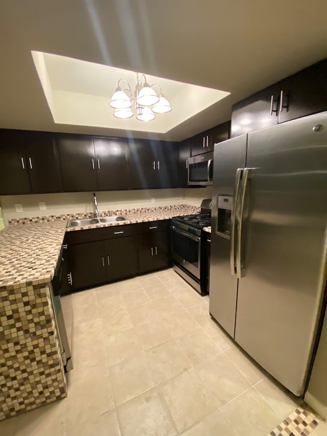 kitchen featuring light tile patterned flooring, a sink, light countertops, dark cabinetry, and stainless steel appliances
